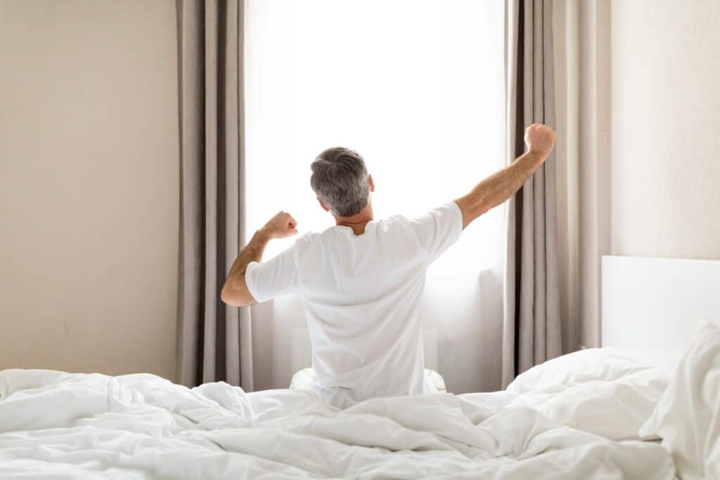 TRT and sleep quality improvement — man stretching after a restful night's sleep